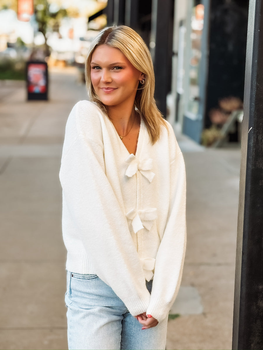 Cream v neck long sleeve sweater with snap button bow ties.