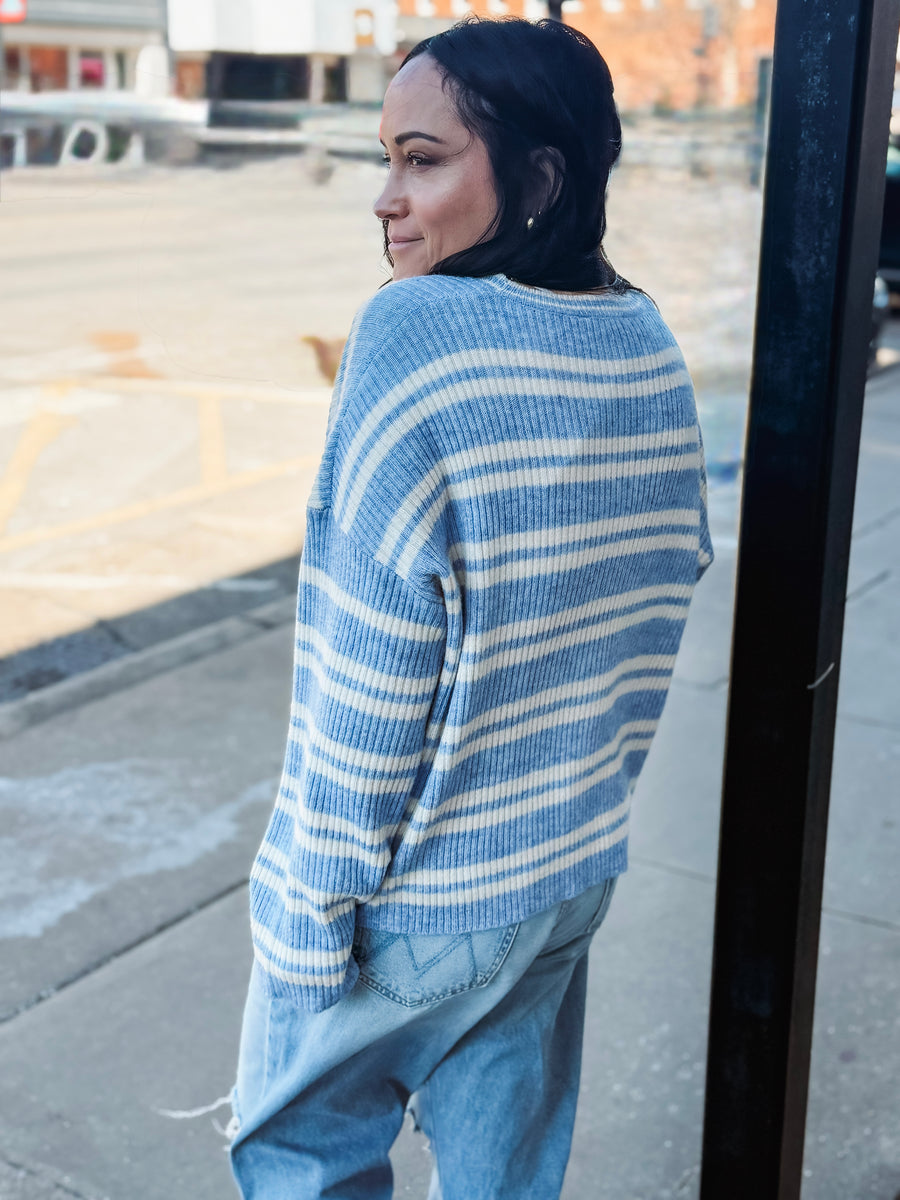 Woman wearing a blue and white striped sweater on a city street.