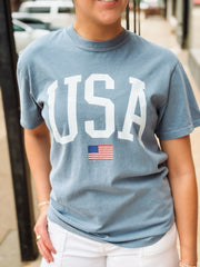 Person wearing a blue t-shirt with 'USA' and an American flag graphic.