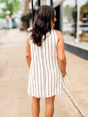 Woman wearing a white and brown striped dress on a city street.