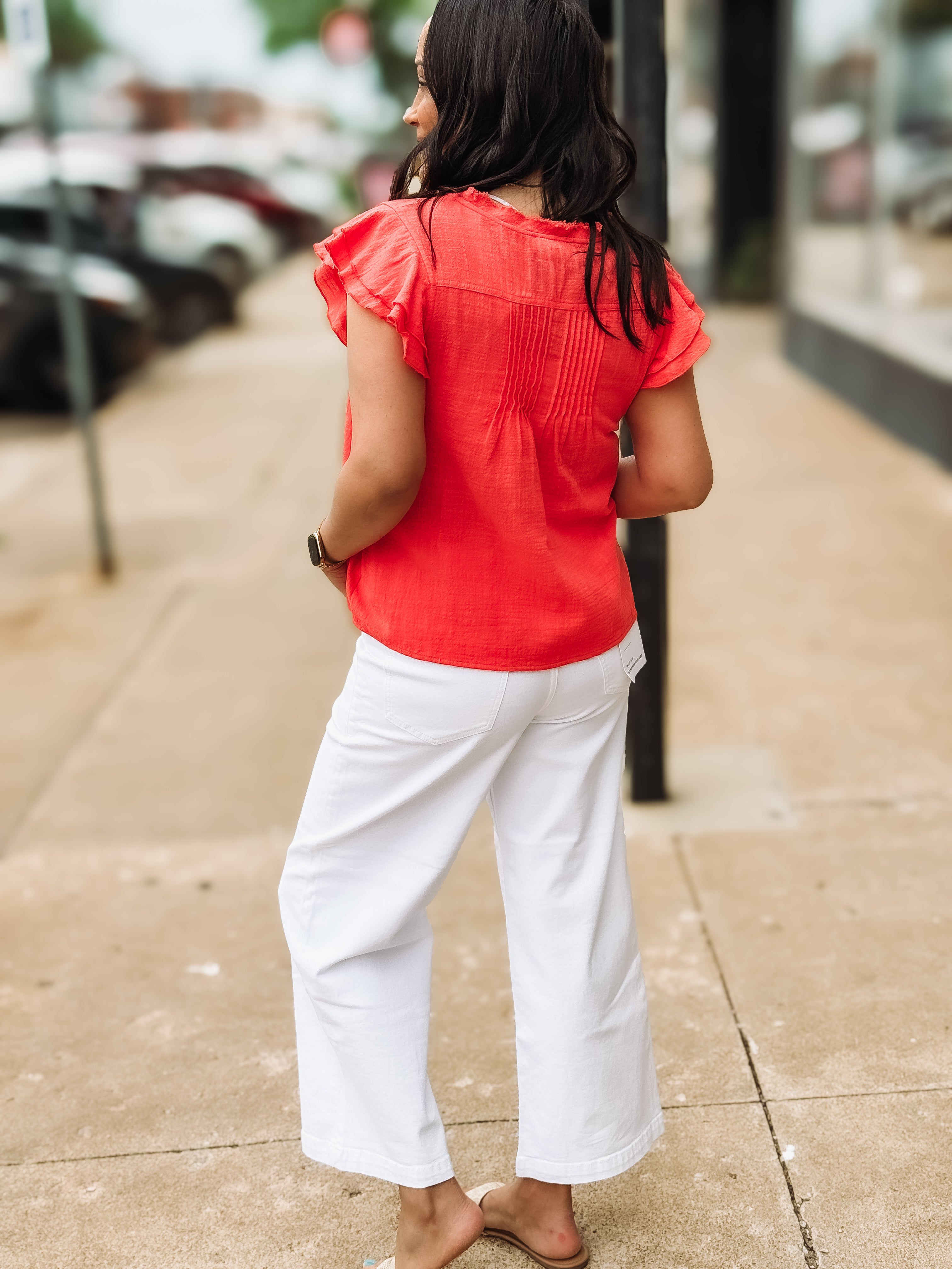 woman on sidewalk wearing red blouse and white pants