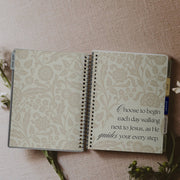 Open notebook with floral design and inspirational quote on a textured surface