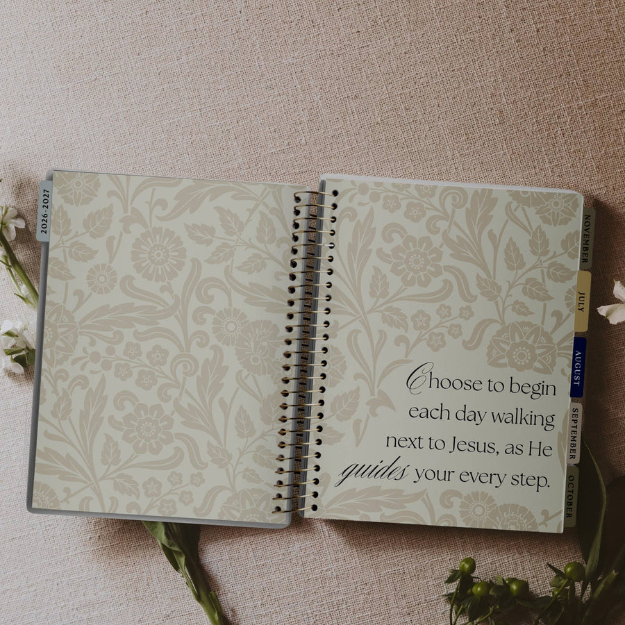 Open notebook with floral design and inspirational quote on a textured surface