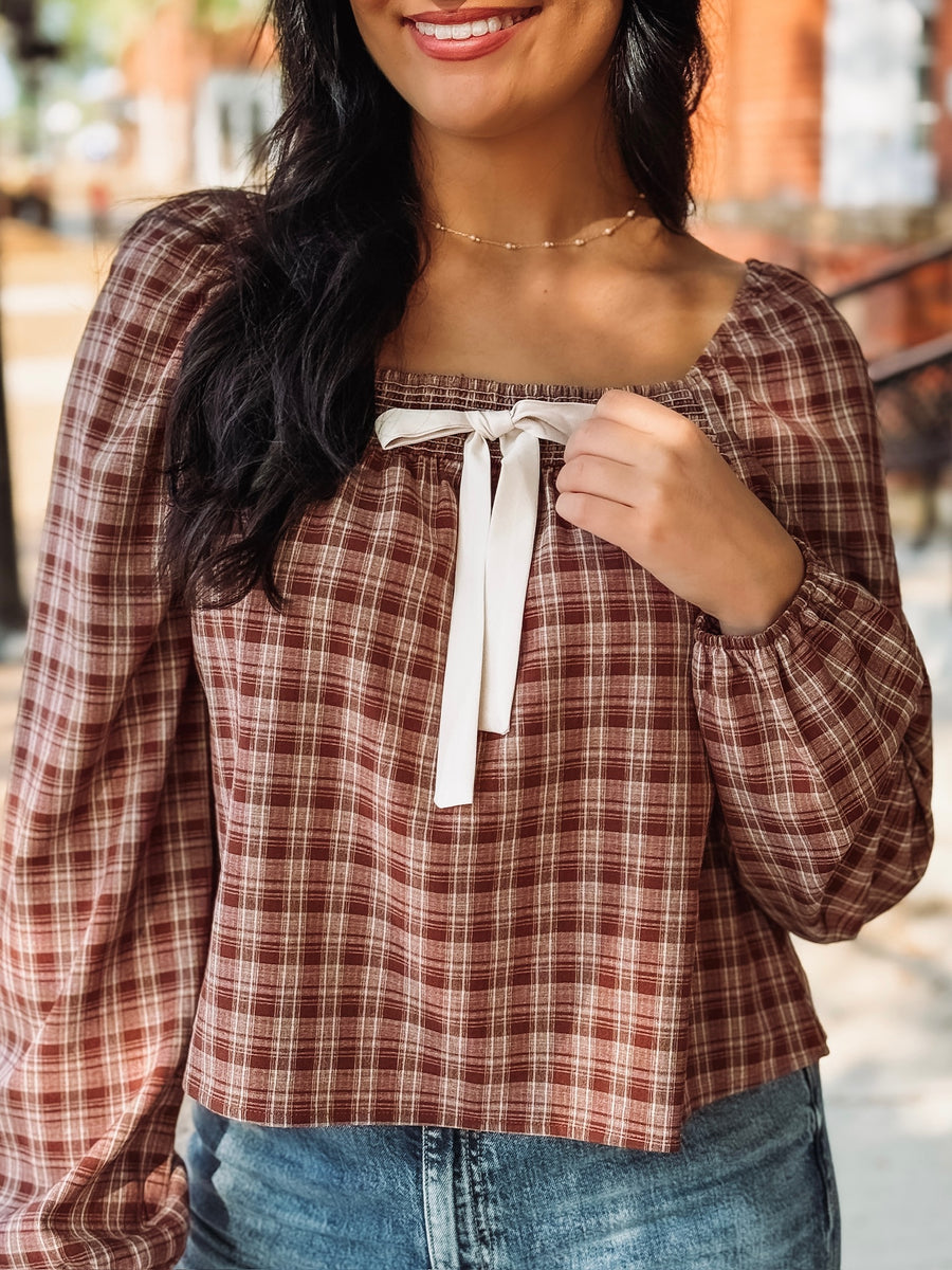 Brick and cream plaid long bubble sleeve top with a square smocked neckline and a self tie bow detail.