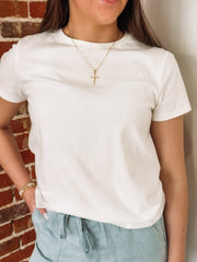 Person wearing a white t-shirt and light blue pants against a brick wall.