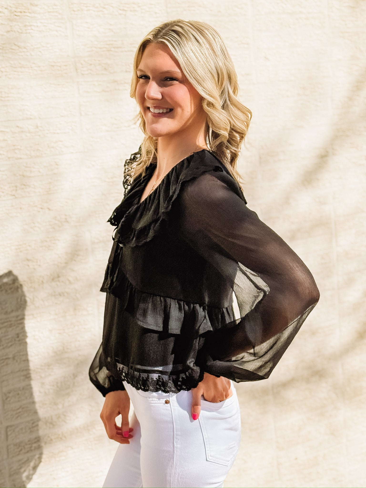 Black long-sleeve blouse featuring a wide ruffled collar with lace trim, sheer balloon sleeves, a ruffled bodice detail, and an intricate lace hemline