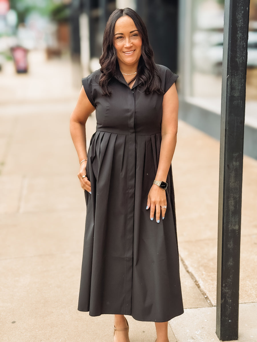 Woman wearing a black dress standing on a sidewalk