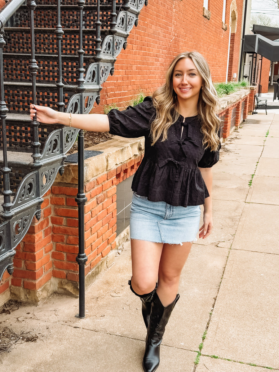 black peplum top with cut out eyelet details and bow tie front
