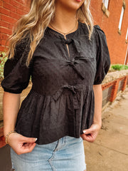 black peplum top with cut out eyelet details and bow tie front