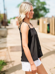 Woman wearing a black sleeveless top and white shorts outdoors.
