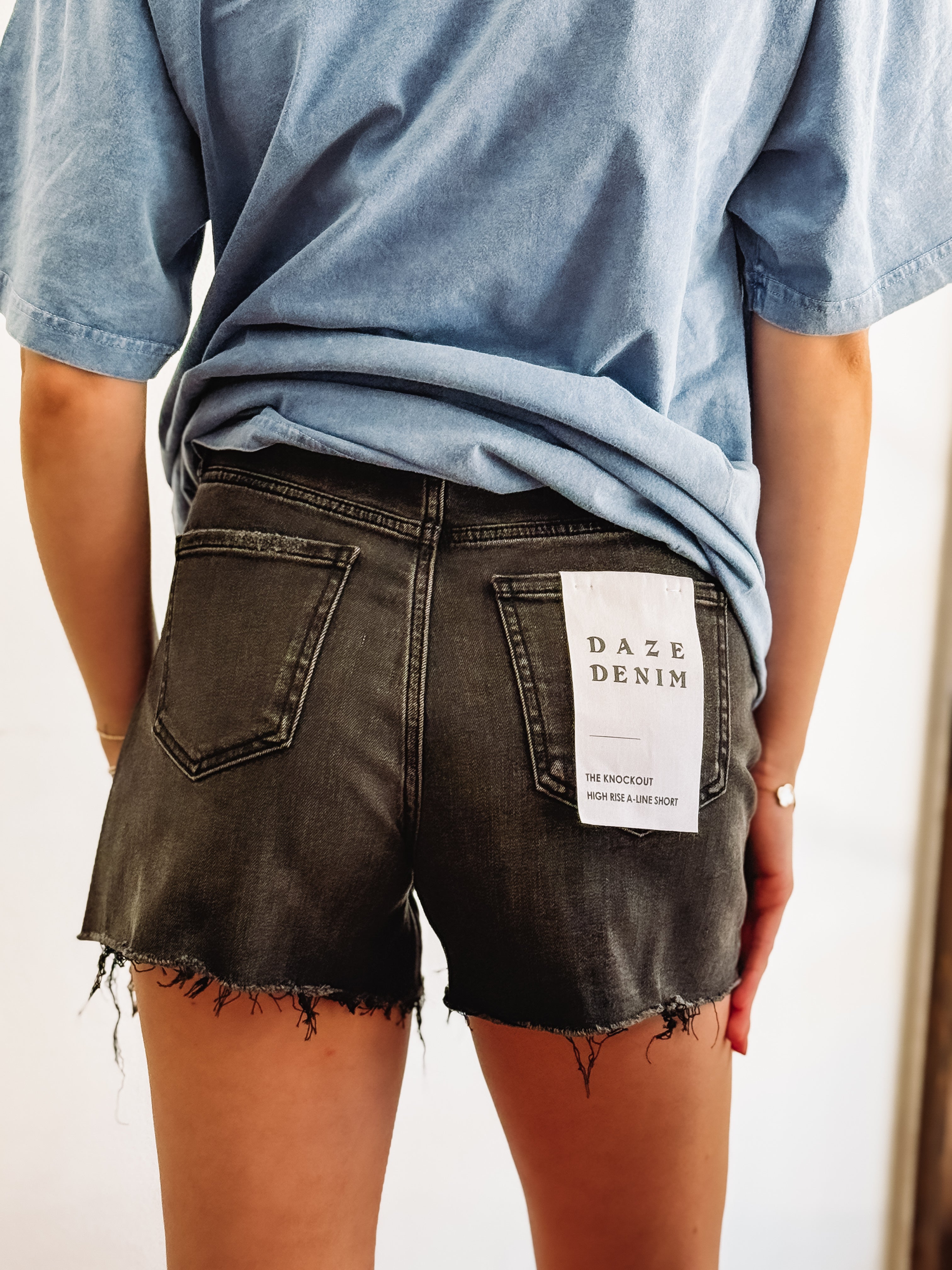 Black distressed denim shorts by Daze.