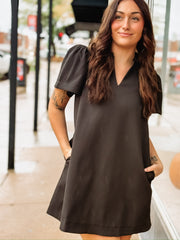 Short-sleeve black V-neck mini dress with side pockets.