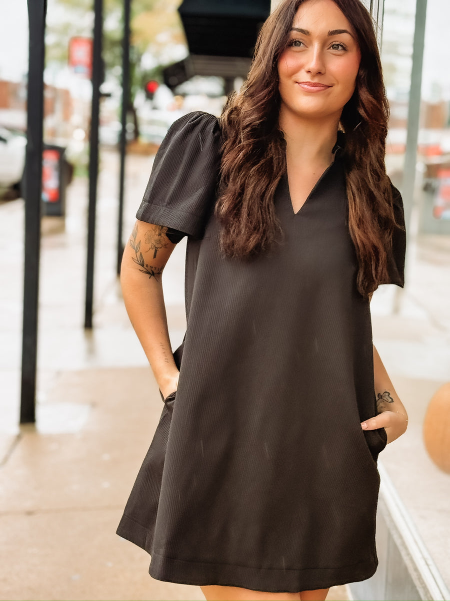 Short-sleeve black V-neck mini dress with side pockets.