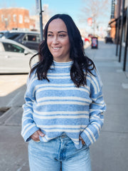 Woman wearing a blue and white striped sweater on a city street.