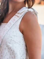 Close-up of a person wearing a white sleeveless top with floral patterns.
