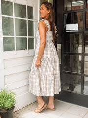 Woman in a brown and white dress standing against a white and black door