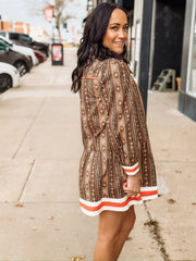 brown long-sleeve printed mini dress with orange and white trim.