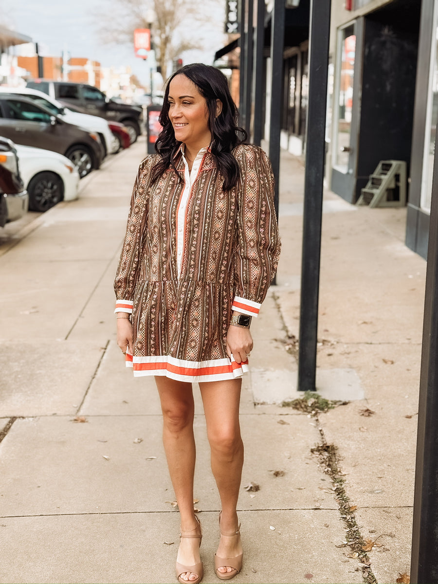 Brown long-sleeve printed mini dress with orange and white trim.
