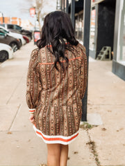 brown long-sleeve printed mini dress with orange and white trim.