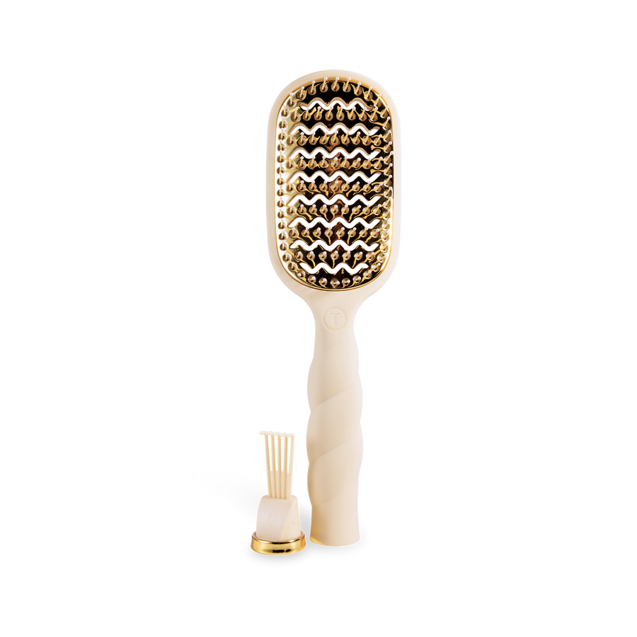 Hairbrush with gold bristle head and white handle on a white background
