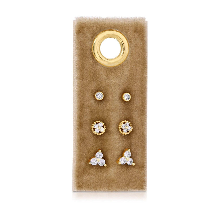 Set of gold and crystal earrings on a brown velvet card with a gold ring design.