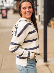 Woman wearing a striped sweater and jeans on a city street.