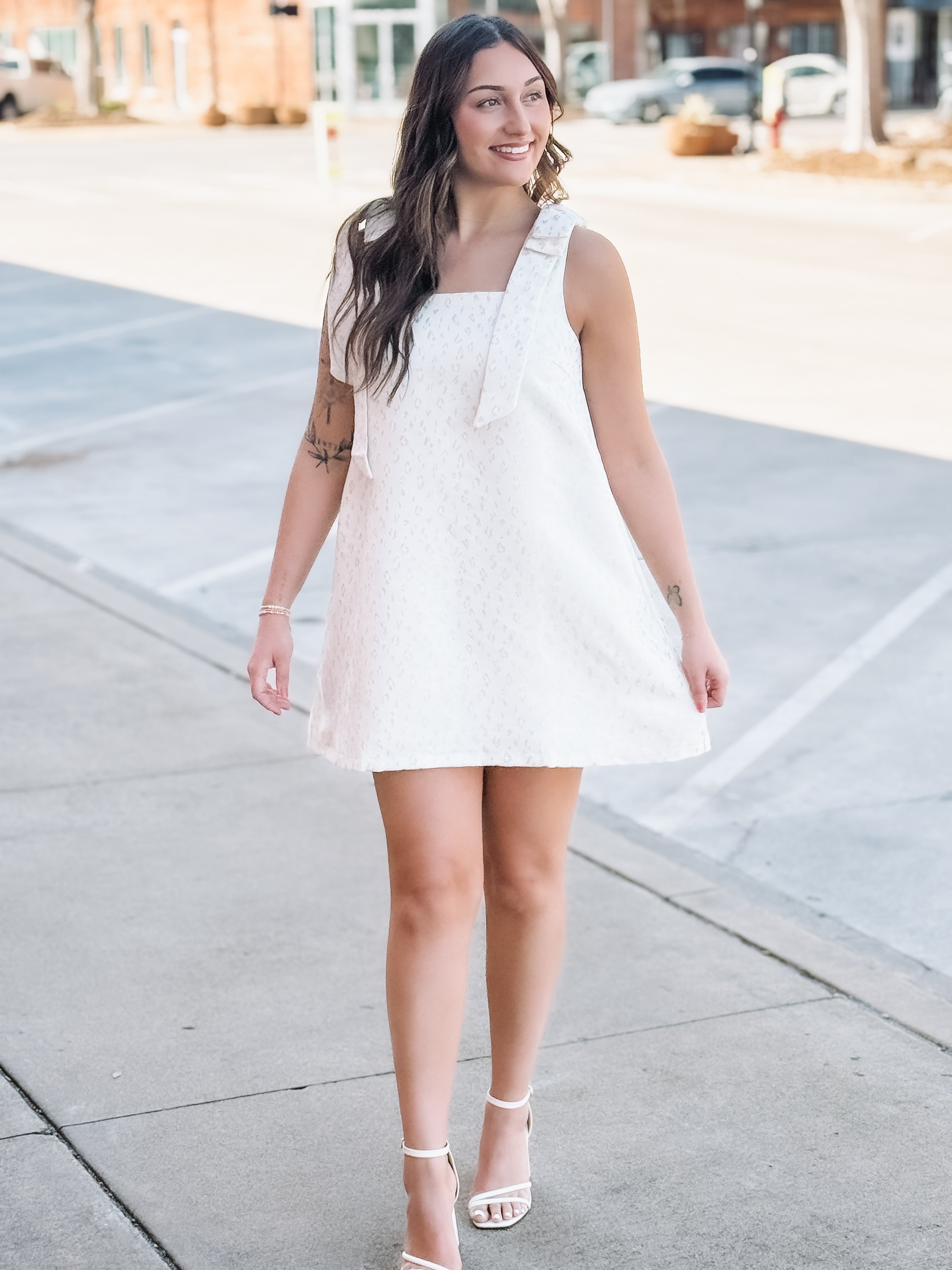 Woman in a white dress standing on a sidewalk
