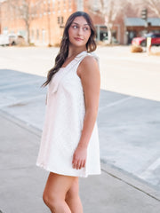 Woman in a white dress standing on a sidewalk with a blurred background