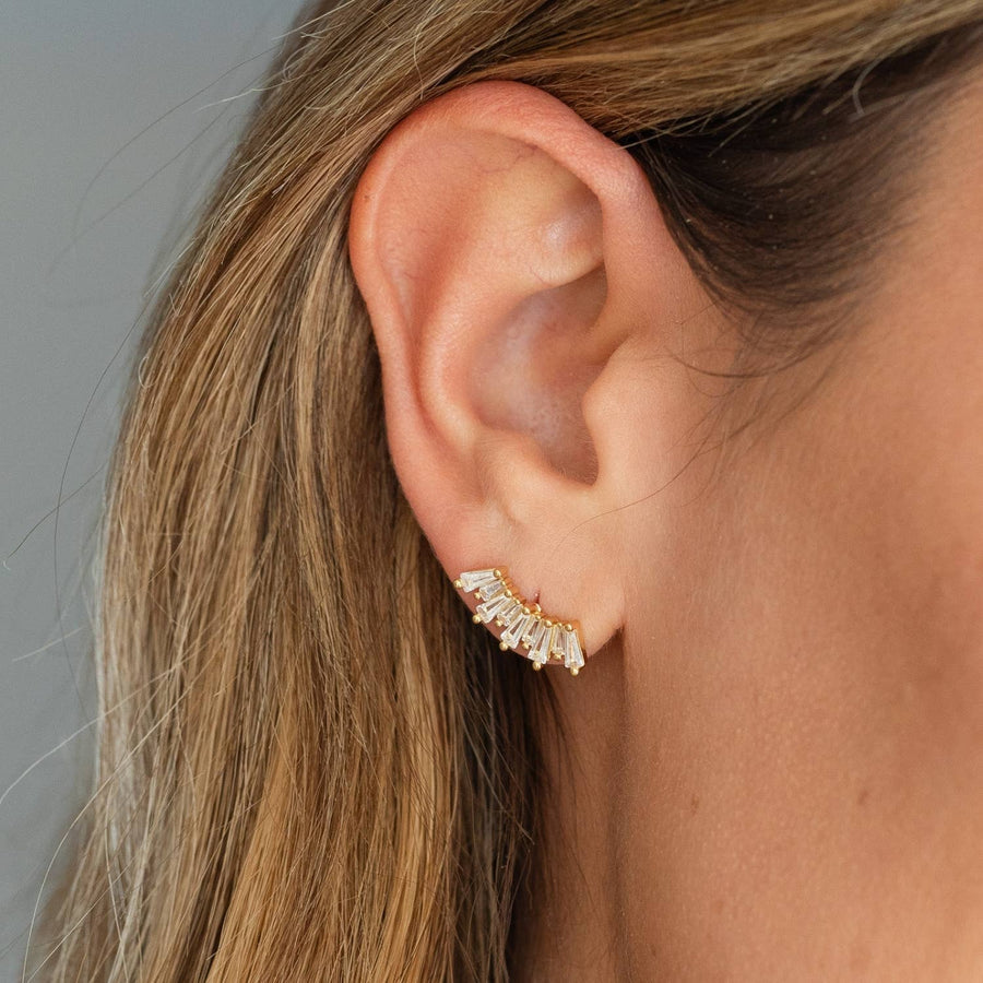 Close-up of an ear wearing a diamond earring with a neutral background