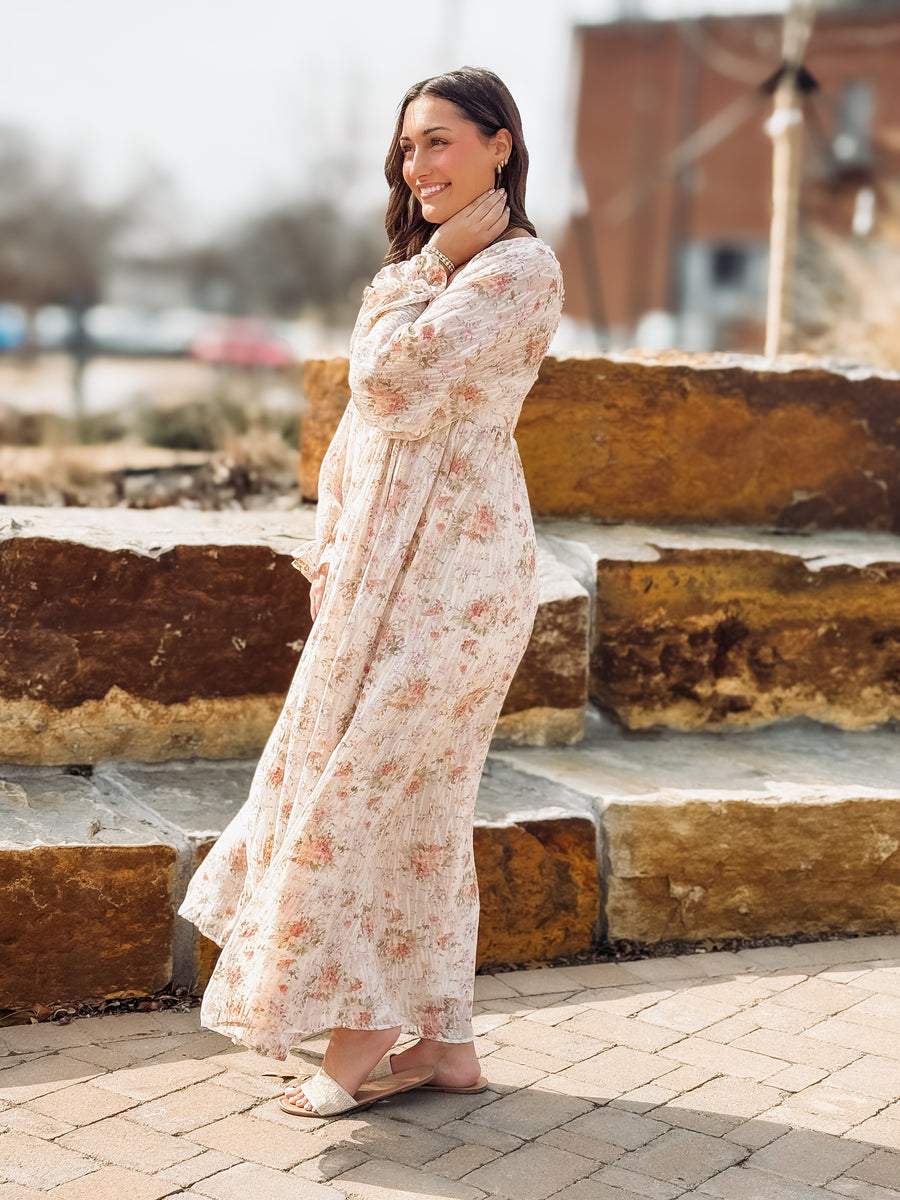 Woman in a floral dress standing outdoors on stone steps.