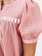 Dusty pink short sleeve baby doll dress with white bow detailing.