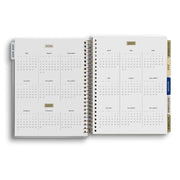 Open spiral-bound planner showing calendar pages from 2021 to 2023 on a white background.