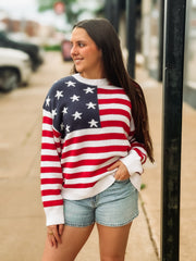 Woman wearing an American flag sweater on a city street.