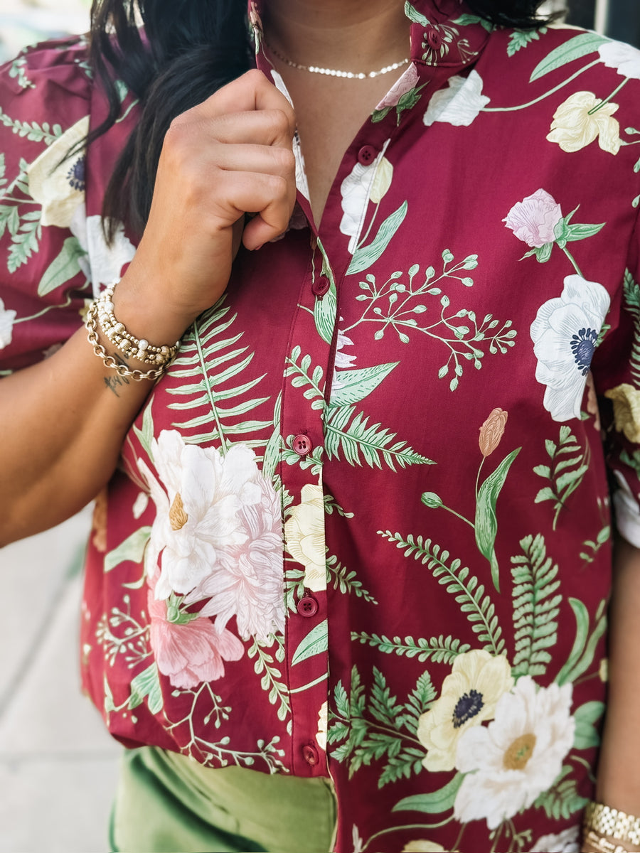 Wine-colored floral blouse with a ruffle neckline and button-up front