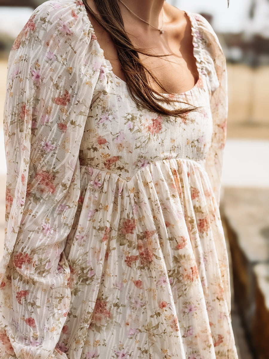 Floral dress with sheer sleeves worn by a person, blurred background