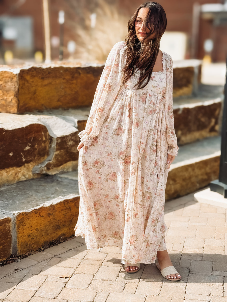 Woman in a floral dress standing outdoors on stone steps.
