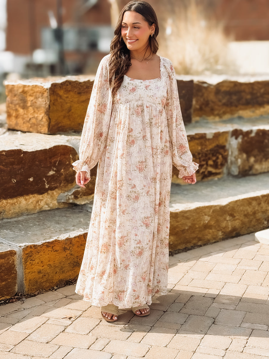 Woman in a floral dress standing outdoors on stone steps.