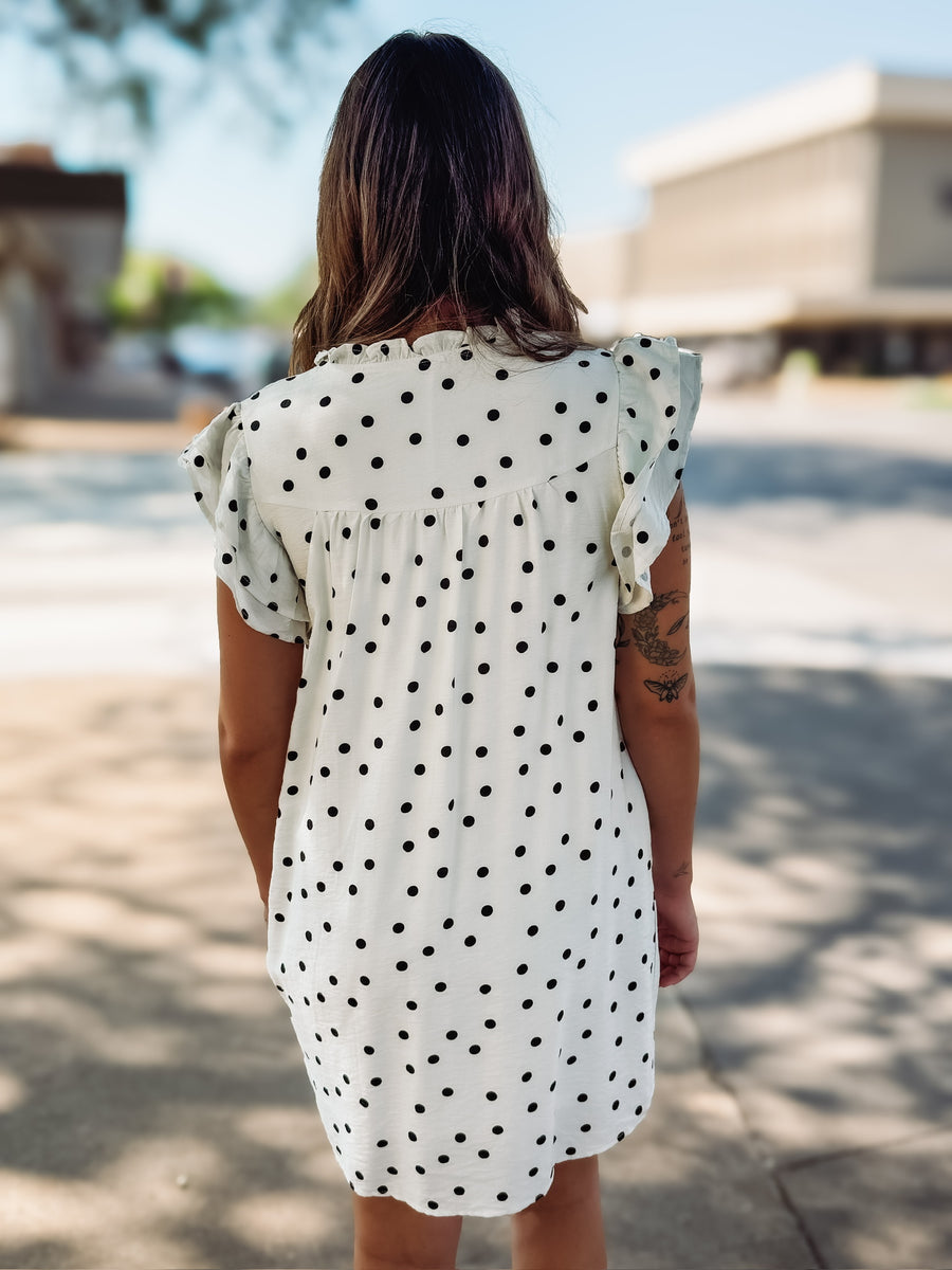 Off white flutter sleeve mini shift dress with black polka dots and a small v neckline.