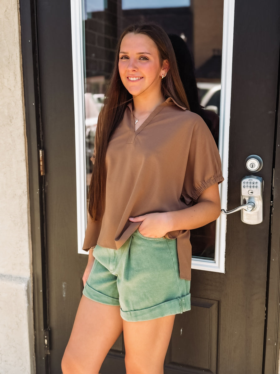 Light wash denim shorts with front pleats and a soft rolled hem, featuring a relaxed, casual fit