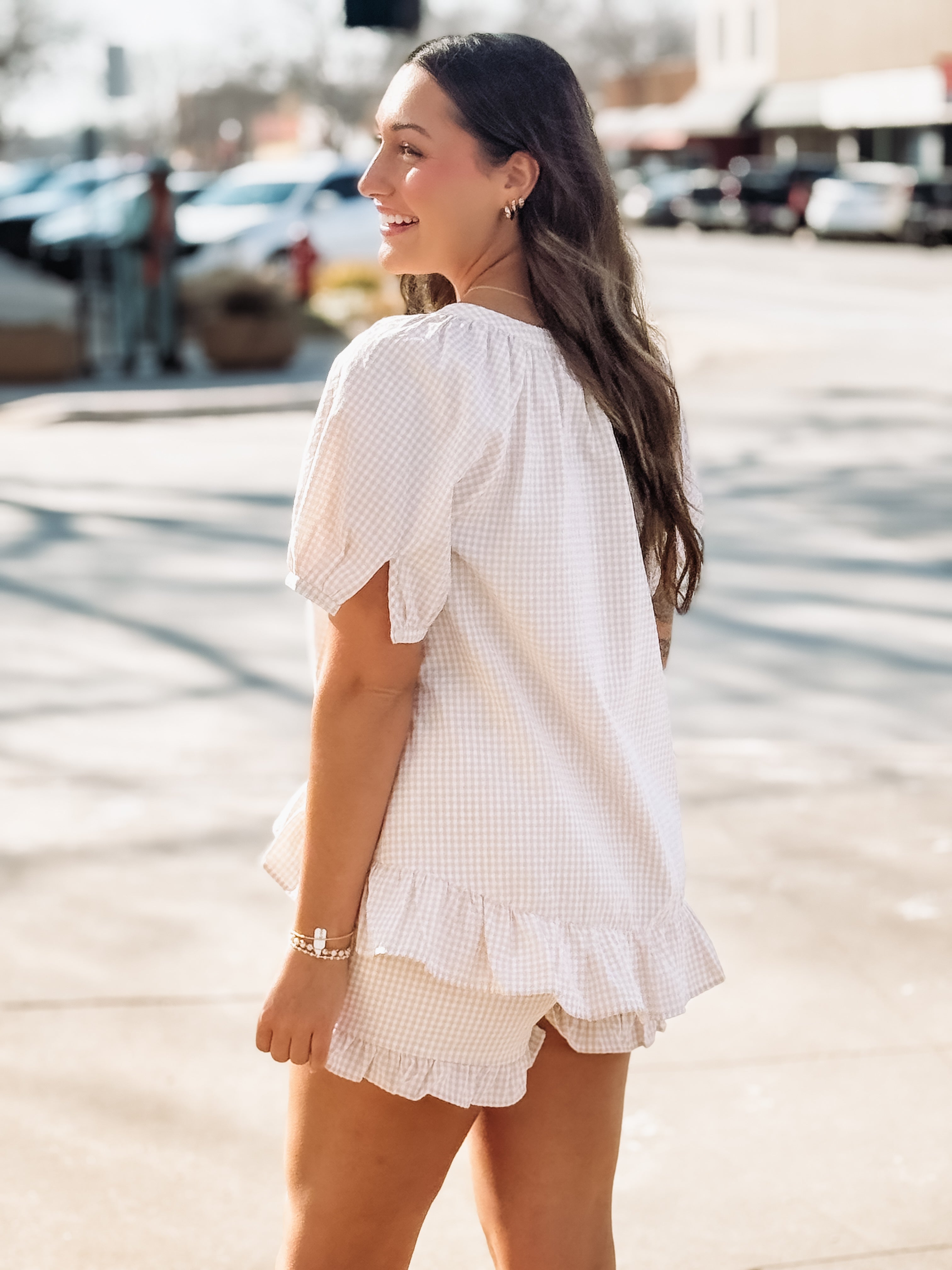 Woman wearing a white outfit with ruffled details in an outdoor setting