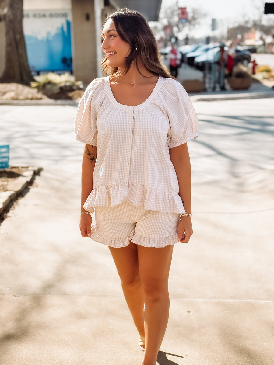 Woman wearing a white blouse and beige shorts on a street.