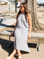 Woman in a checkered dress sitting on a bench outdoors.