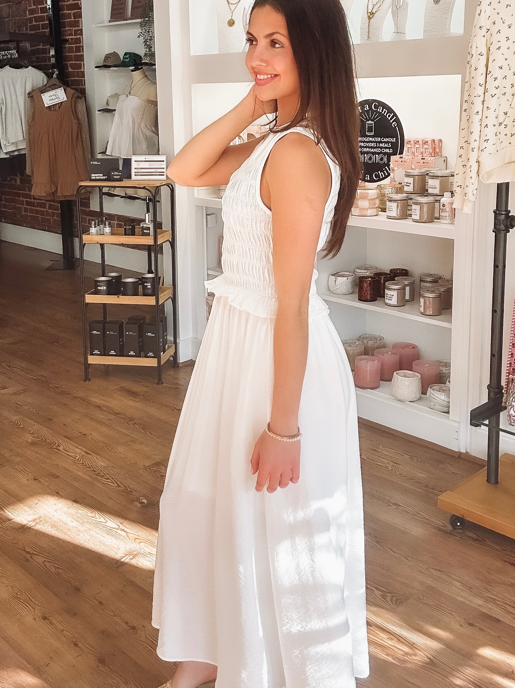 Woman in a white dress standing in a store with shelves in the background