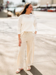 Woman wearing a white sweater and beige pants on a city street.