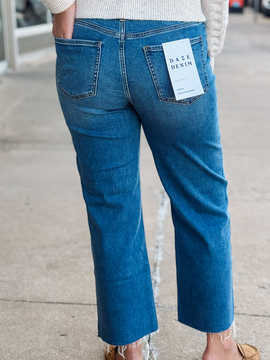 Person wearing blue jeans with a brand tag on a blurred street background