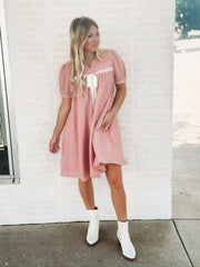 Dusty pink short sleeve baby dol dress with white bow detailing.