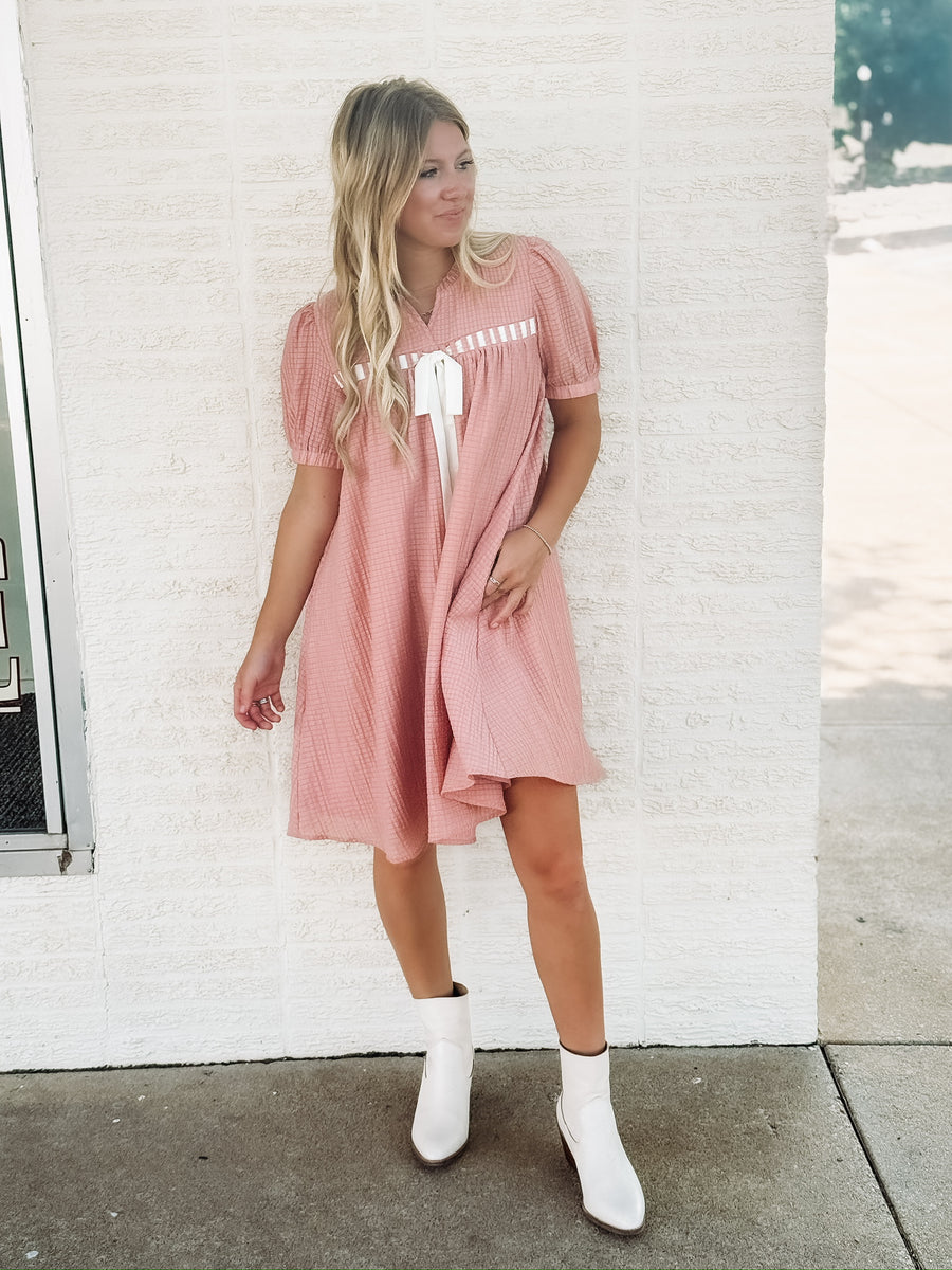 Dusty pink short sleeve baby dol dress with white bow detailing.