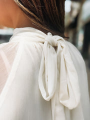 Close-up of a white blouse with a bow detail on a blurred background