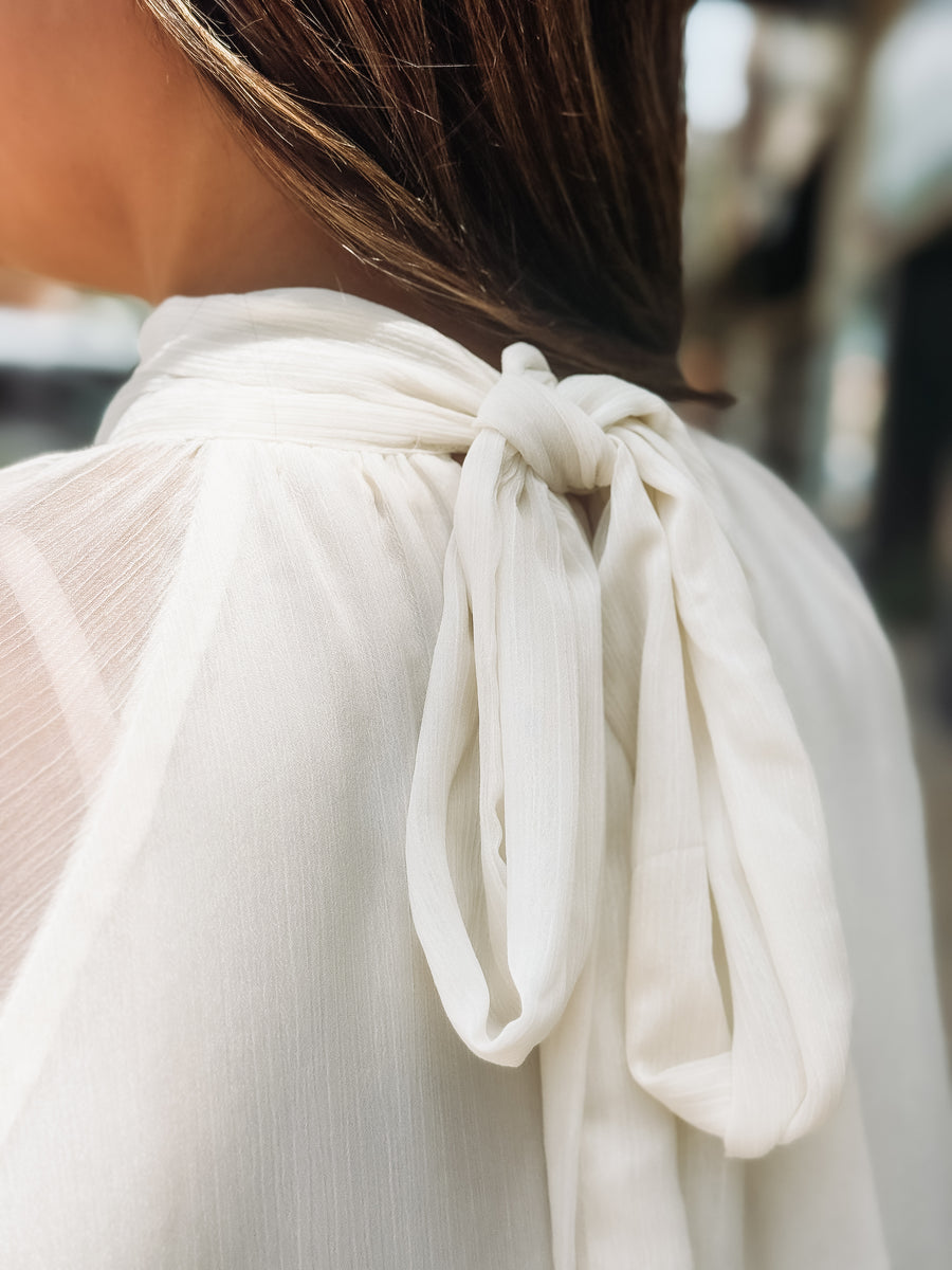 Close-up of a white blouse with a bow detail on a blurred background