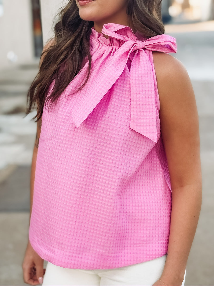 Textured pink top featuring a feminine bow tie neckline and relaxed fit